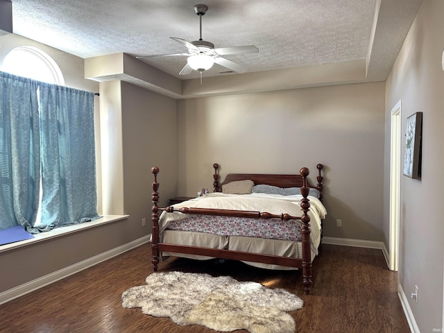 bedroom featuring ceiling fan, dark hardwood / wood-style flooring, and a textured ceiling