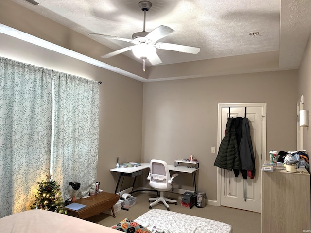 bedroom featuring a raised ceiling, ceiling fan, and a textured ceiling