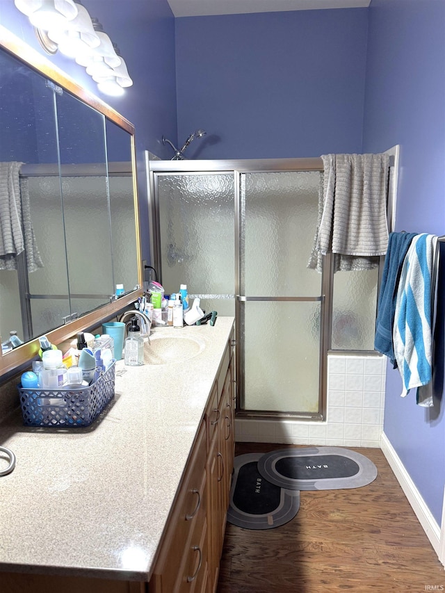 bathroom with walk in shower, vanity, and hardwood / wood-style flooring