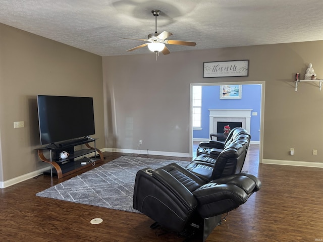 living room with ceiling fan, dark wood-type flooring, and a textured ceiling