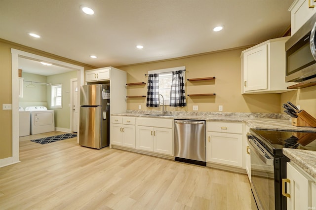 kitchen featuring stainless steel appliances, washer and clothes dryer, sink, light hardwood / wood-style flooring, and white cabinetry