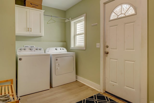 laundry area with separate washer and dryer, a wealth of natural light, cabinets, and light hardwood / wood-style floors