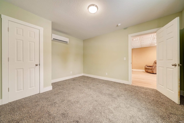 empty room featuring carpet, a textured ceiling, and a wall mounted AC