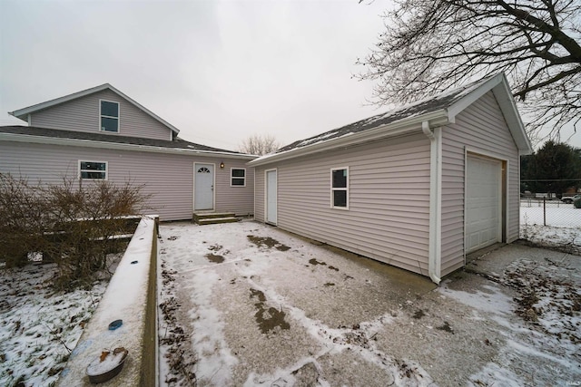 snow covered back of property with an outbuilding and a garage