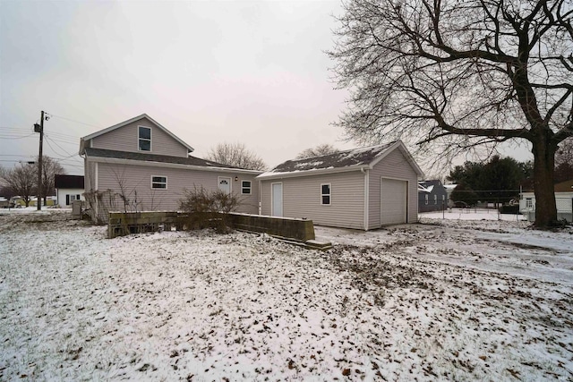 snow covered property featuring a garage and an outdoor structure