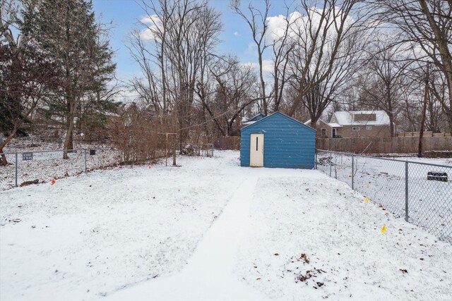 snowy yard featuring a storage unit