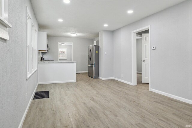 kitchen with white cabinets, stainless steel fridge, and light wood-type flooring