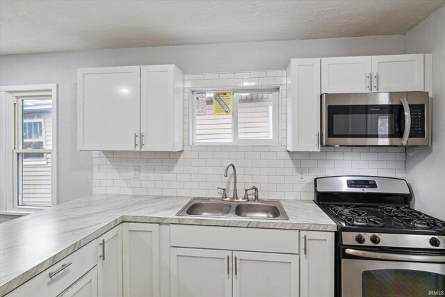 kitchen featuring tasteful backsplash, white cabinetry, sink, and appliances with stainless steel finishes