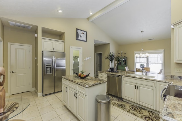 kitchen with light stone counters, stainless steel appliances, sink, pendant lighting, and a kitchen island