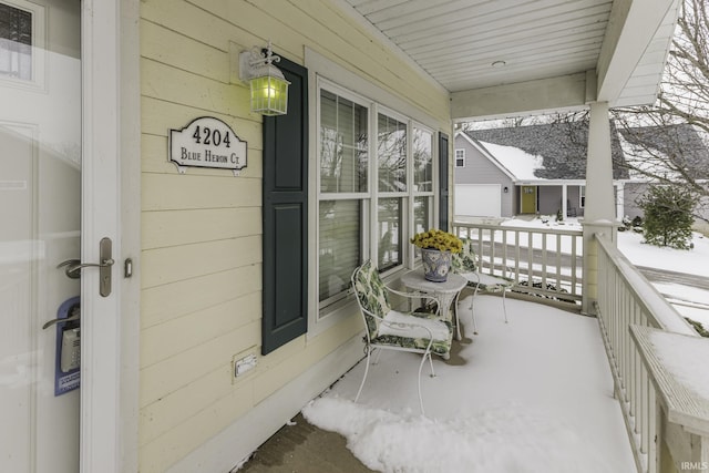 snow covered back of property with covered porch