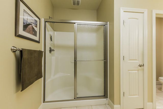 bathroom featuring tile patterned flooring, toilet, and an enclosed shower