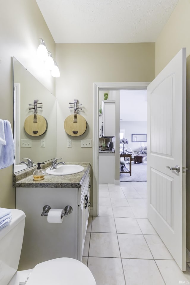 bathroom with tile patterned floors, vanity, a textured ceiling, and toilet