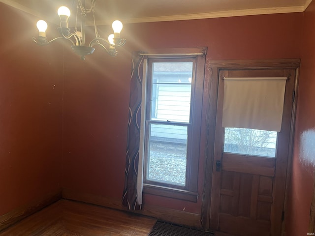 doorway with ornamental molding and an inviting chandelier