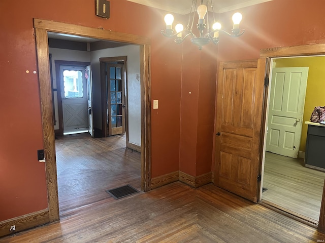 corridor with hardwood / wood-style floors and an inviting chandelier