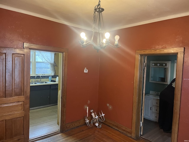 unfurnished dining area with a notable chandelier, wood-type flooring, ornamental molding, and sink