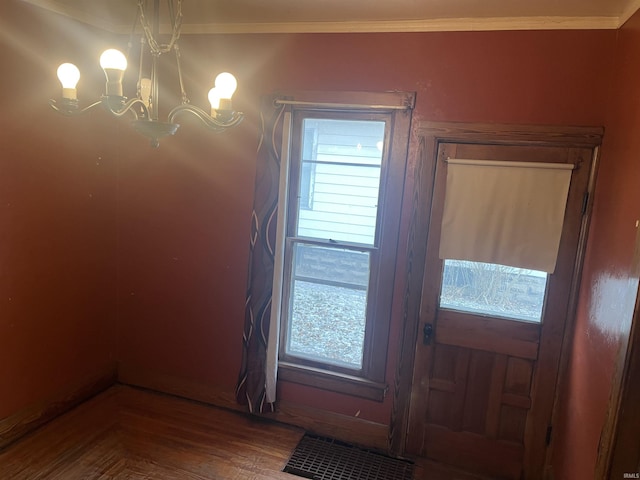 doorway to outside featuring wood-type flooring, crown molding, and a chandelier