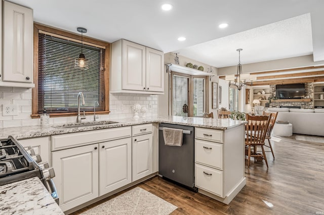 kitchen with dark wood-type flooring, sink, appliances with stainless steel finishes, decorative light fixtures, and kitchen peninsula