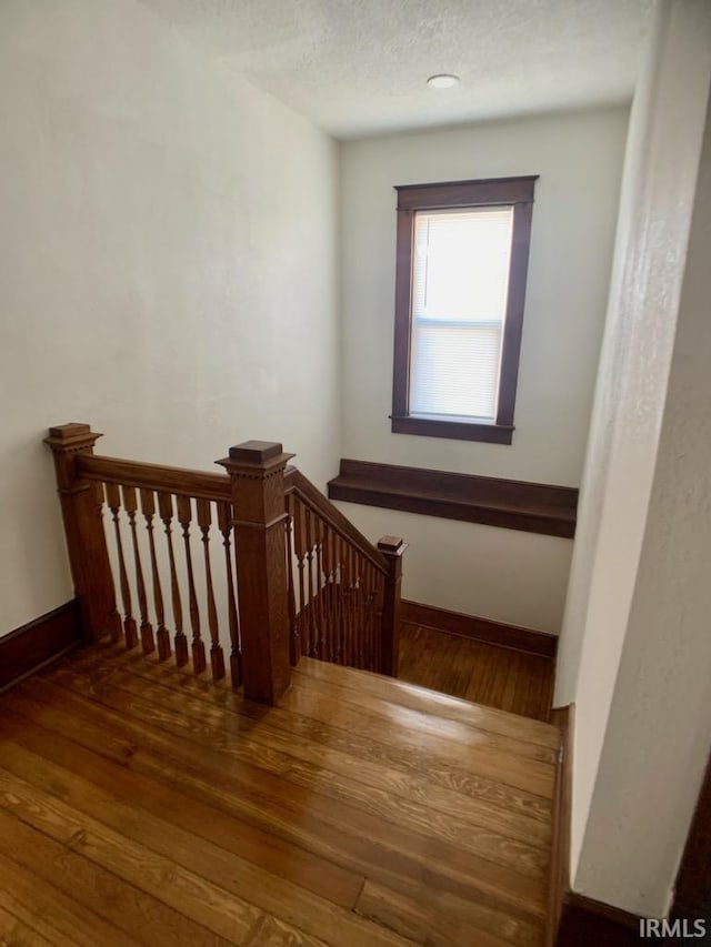 staircase with wood-type flooring and a textured ceiling