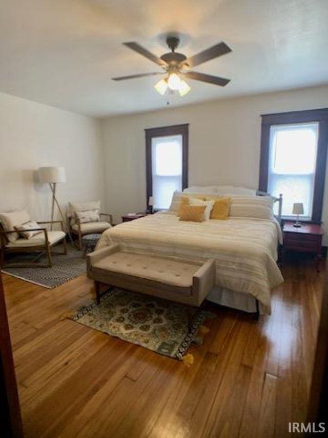 bedroom with multiple windows, ceiling fan, and dark hardwood / wood-style flooring