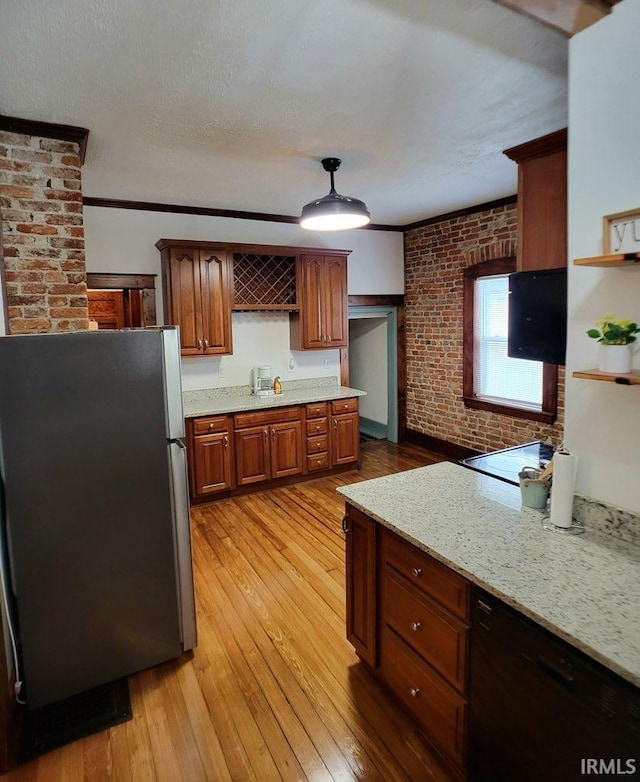 kitchen with black dishwasher, light stone counters, brick wall, stainless steel fridge, and light wood-type flooring