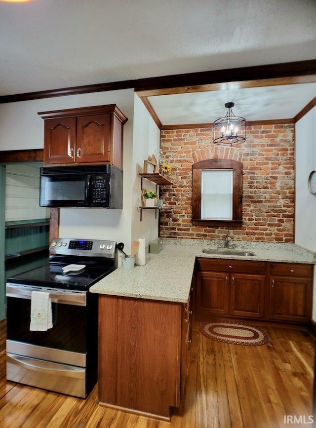 kitchen with light stone counters, brick wall, sink, electric range, and an inviting chandelier