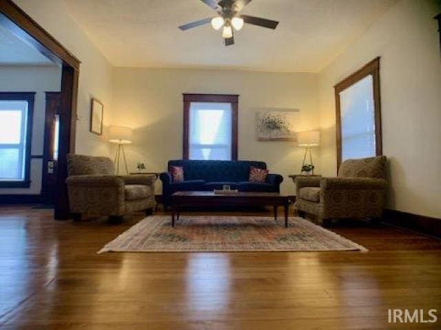 living room featuring ceiling fan, dark wood-type flooring, and a healthy amount of sunlight