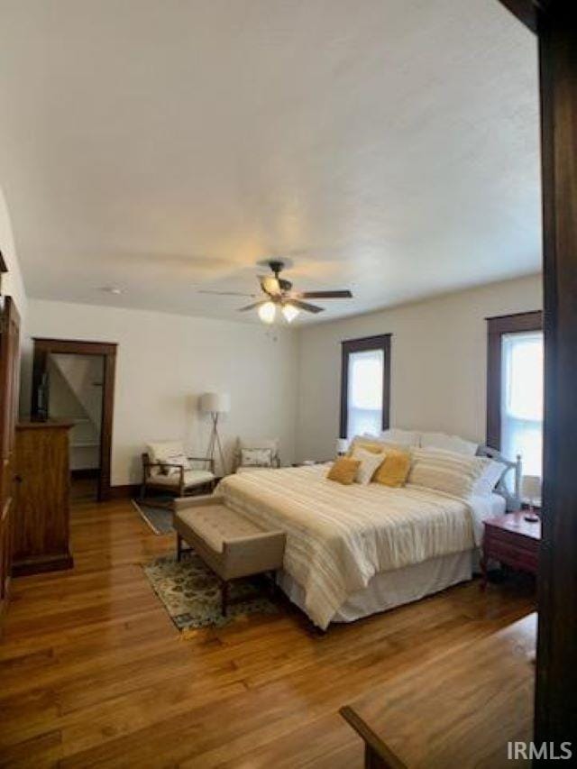 bedroom with multiple windows, ceiling fan, and hardwood / wood-style flooring