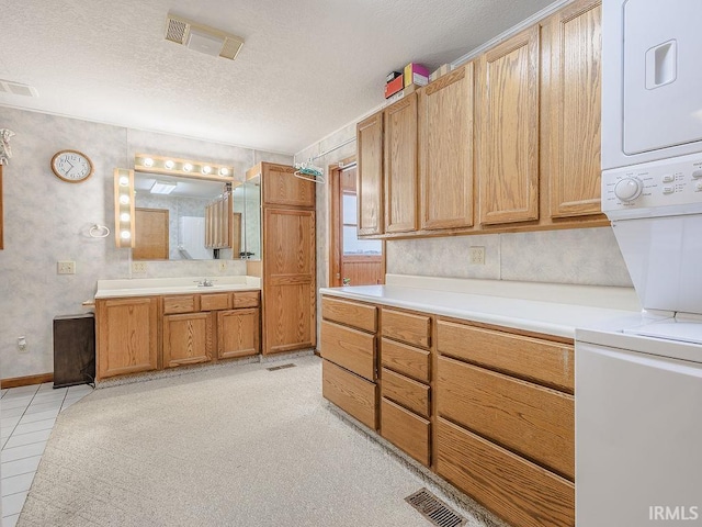 interior space featuring stacked washer / dryer, sink, a textured ceiling, and tile patterned flooring