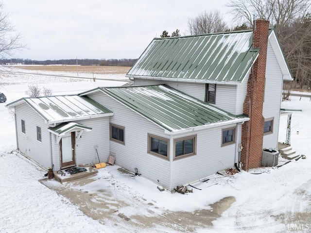 snow covered rear of property featuring central air condition unit