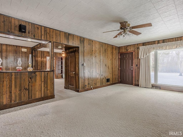 carpeted spare room featuring ceiling fan and wood walls