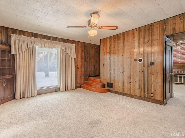 carpeted empty room featuring ceiling fan and wood walls