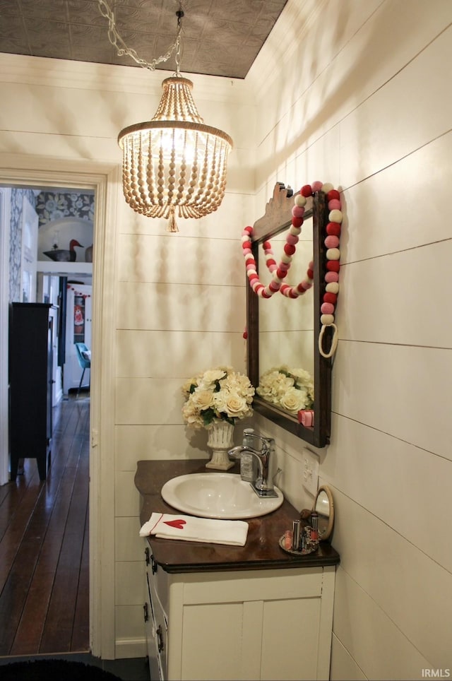 bathroom with wood walls, vanity, and a notable chandelier