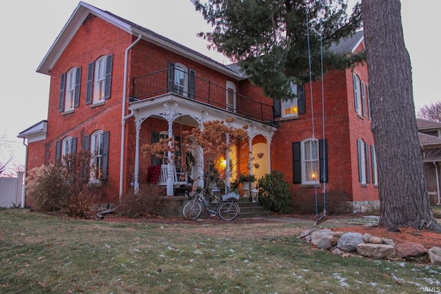 view of front of property featuring a porch, a balcony, and a front yard