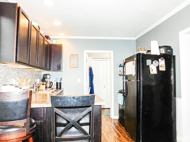 kitchen featuring black refrigerator, dark brown cabinets, light wood-type flooring, and sink