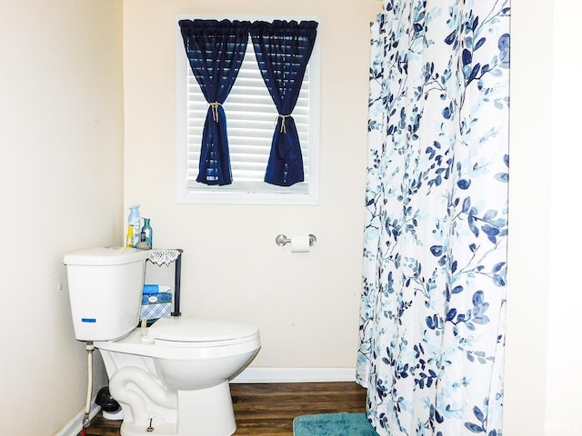 bathroom featuring curtained shower, toilet, and wood-type flooring