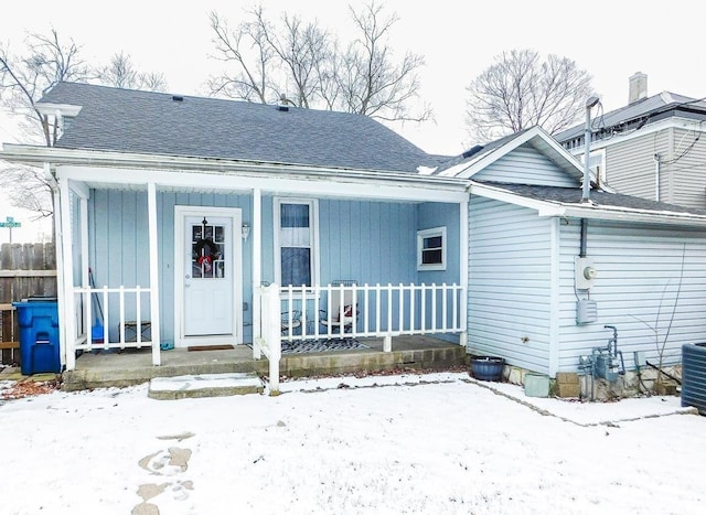 snow covered rear of property featuring covered porch