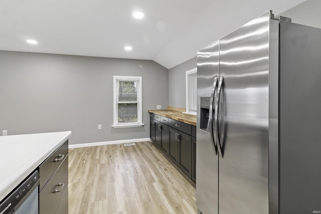 kitchen with wooden counters, appliances with stainless steel finishes, light hardwood / wood-style flooring, and vaulted ceiling