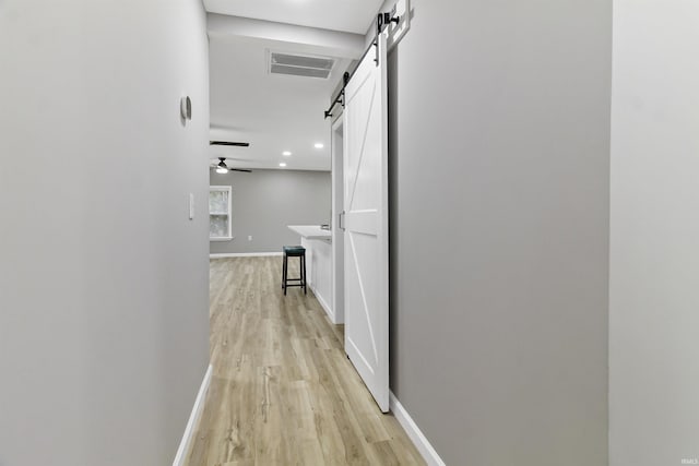 hallway with a barn door and light hardwood / wood-style flooring