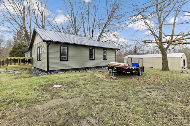 view of side of property featuring a wooden deck, a yard, and an outbuilding