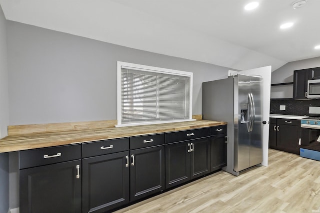 kitchen featuring wooden counters, decorative backsplash, light wood-type flooring, and stainless steel appliances