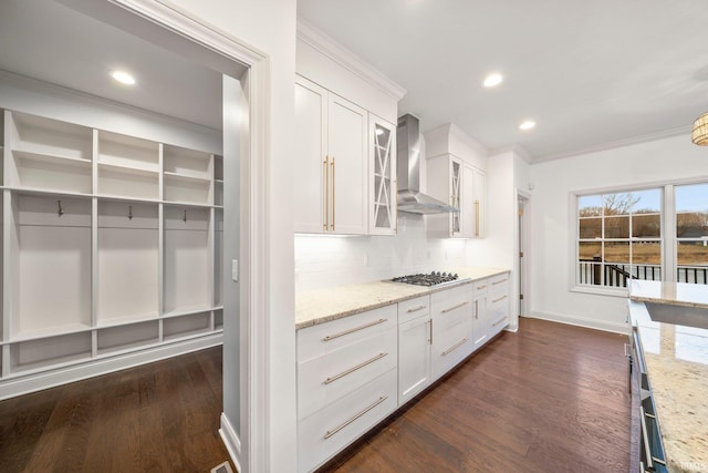 kitchen featuring white cabinets, wall chimney exhaust hood, decorative backsplash, and light stone countertops