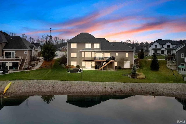 back house at dusk with a yard and a deck with water view