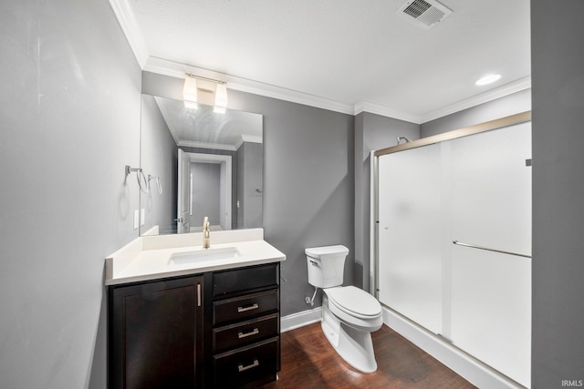 bathroom featuring ornamental molding, vanity, wood-type flooring, toilet, and a shower with shower door