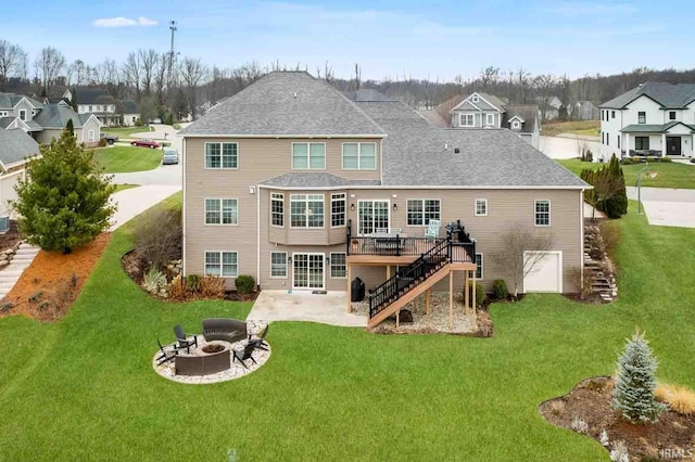 back of property with a fire pit, a deck, and a lawn