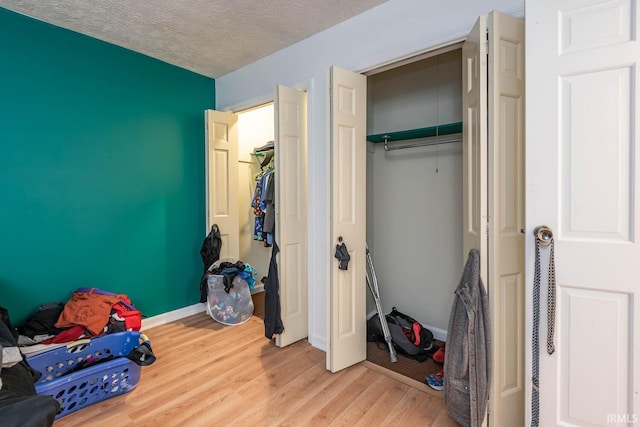 bedroom featuring light hardwood / wood-style flooring, a textured ceiling, and a closet