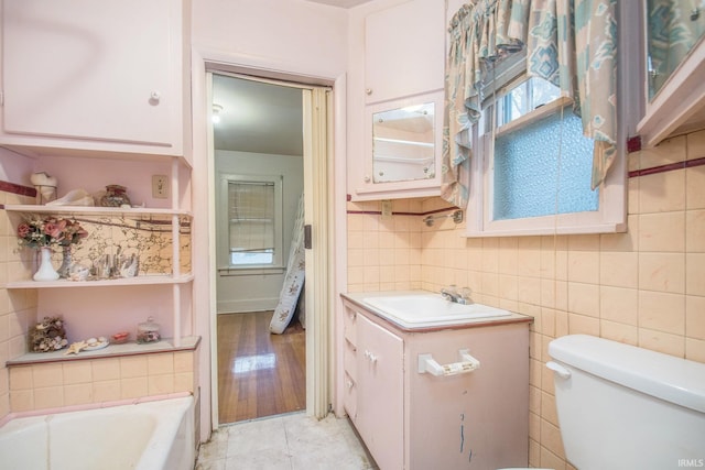 bathroom featuring tile patterned flooring, vanity, toilet, and a tub to relax in