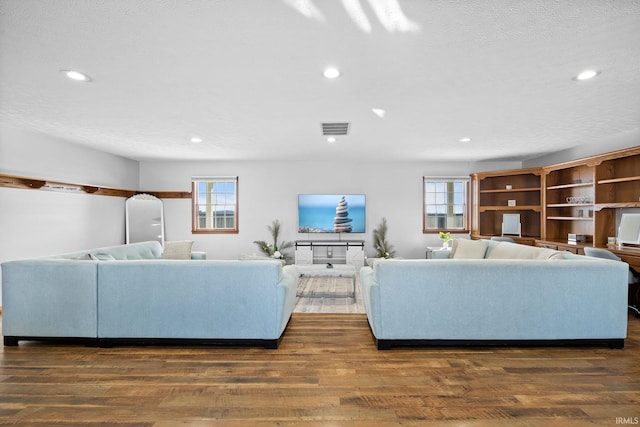 living room with a textured ceiling and dark wood-type flooring