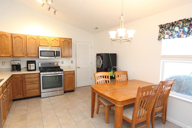 kitchen featuring pendant lighting, lofted ceiling, an inviting chandelier, light tile patterned floors, and stainless steel appliances