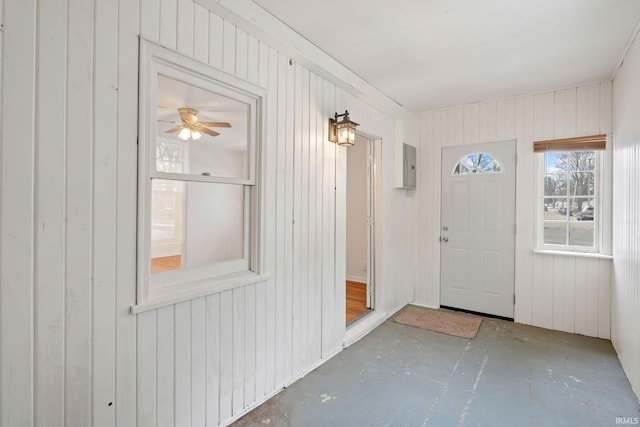 foyer featuring electric panel, ceiling fan, and wood walls