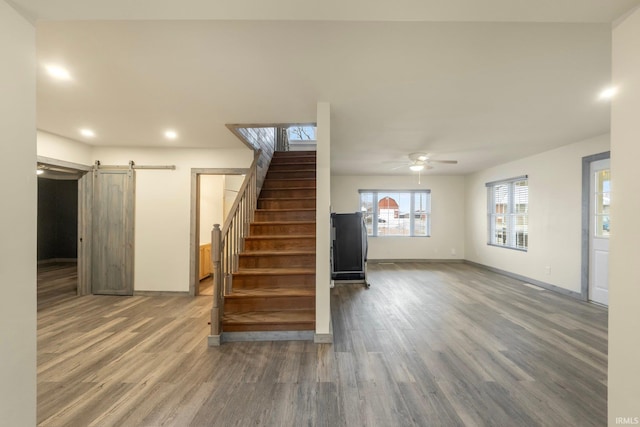 interior space with a barn door, ceiling fan, and hardwood / wood-style flooring